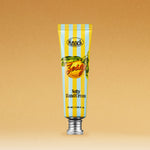 A tube of SOFTY HAND CREAM ZESTY, featuring blue and yellow stripes, an orange fruit graphic, and a silver cap, set against a brown background.