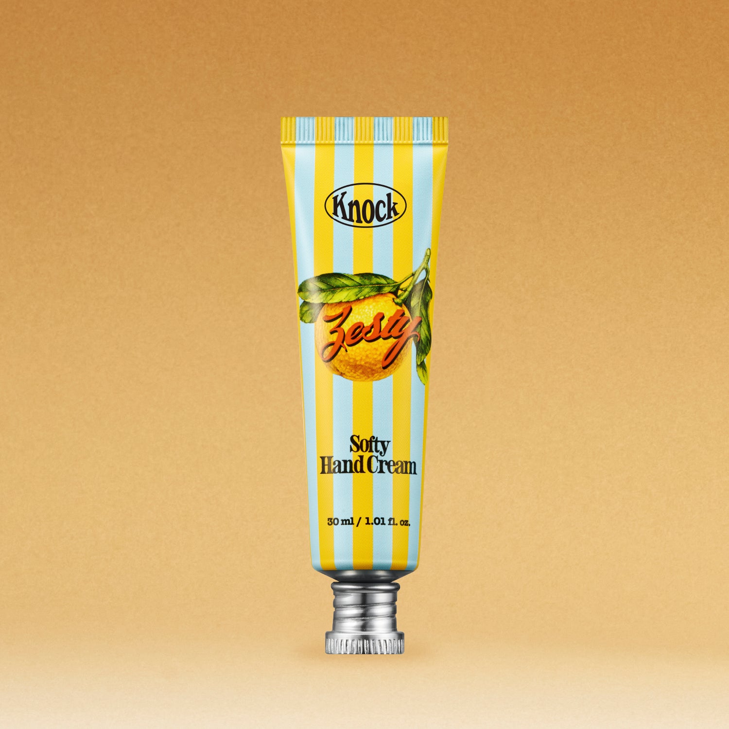 A tube of SOFTY HAND CREAM ZESTY, featuring blue and yellow stripes, an orange fruit graphic, and a silver cap, set against a brown background.