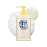 A bottle of WHIPPING MILK WASH SEOUL VANILLA with a yellow pump sits amidst white foam and a swirl of creamy liquid on a white background—this hydrating body wash envelops your skin in rich moisture with every use.