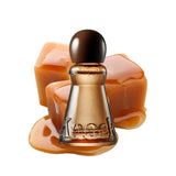 A bottle of Knock perfume with amber-brown glass, a dark round cap, and embossed lettering, styled with caramel-colored chunks and a pool of caramel on a white background.
