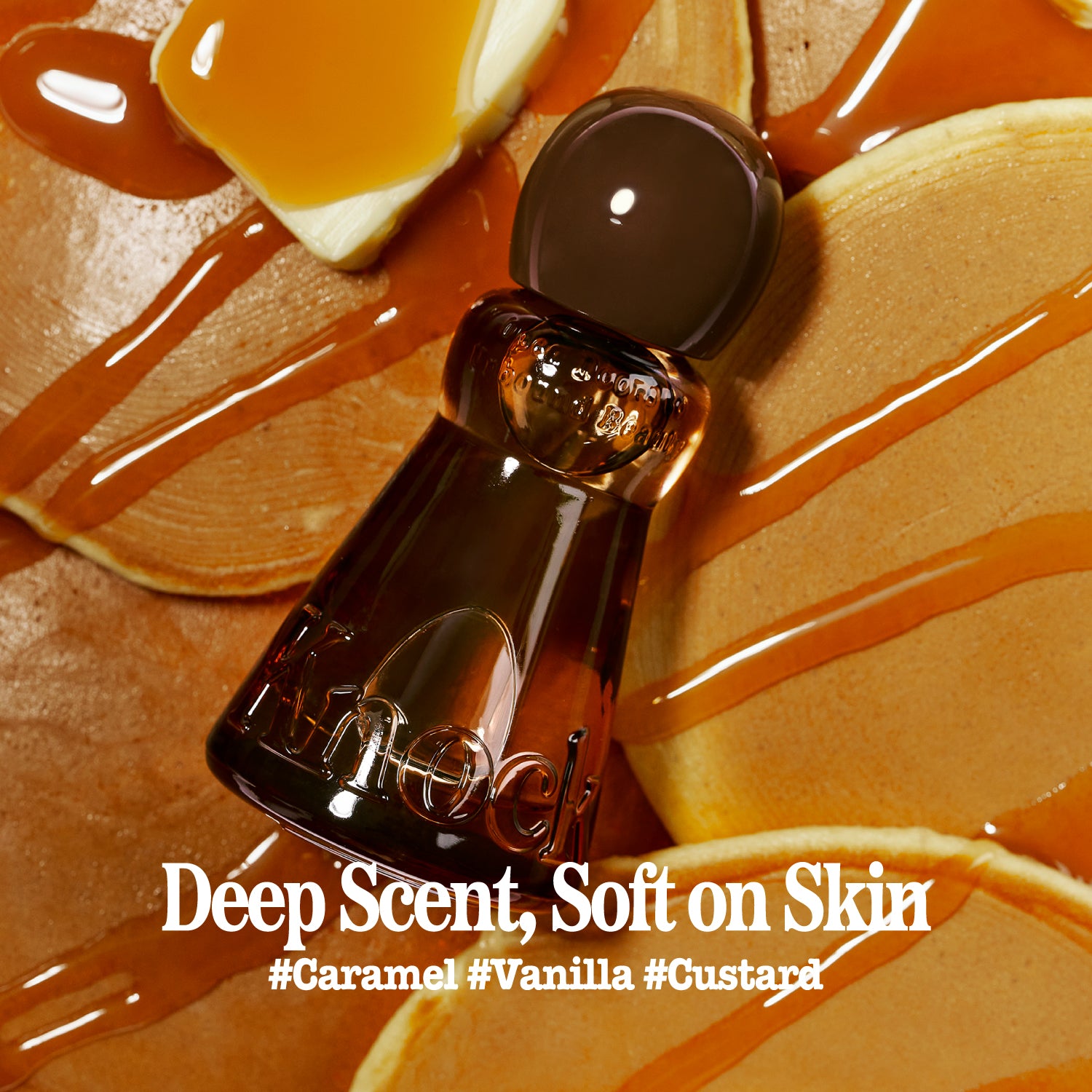 A close-up of a dark amber glass perfume bottle with a rounded dark cap, placed on a warm caramel and vanilla-toned surface with glossy drizzle and text reading 'Deep Scent, Soft on Skin' and '#Caramel #Vanilla #Custard'.