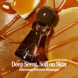 A close-up of a dark amber glass perfume bottle with a rounded dark cap, placed on a warm caramel and vanilla-toned surface with glossy drizzle and text reading 'Deep Scent, Soft on Skin' and '#Caramel #Vanilla #Custard'.