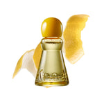 A bottle of Kroek Coco de Coco Beach perfume with a yellow cap and golden-yellow liquid, styled with lemon peel slices on a white background.