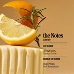 A styled fragrance or cosmetic shade card reading 'the Notes ZESTY' with scent notes 'ON SKIN' and 'MELT IN SKIN.' The design shows a cream-colored textured block topped with a lemon slice, orange peel, and rosemary sprig against a warm beige background.