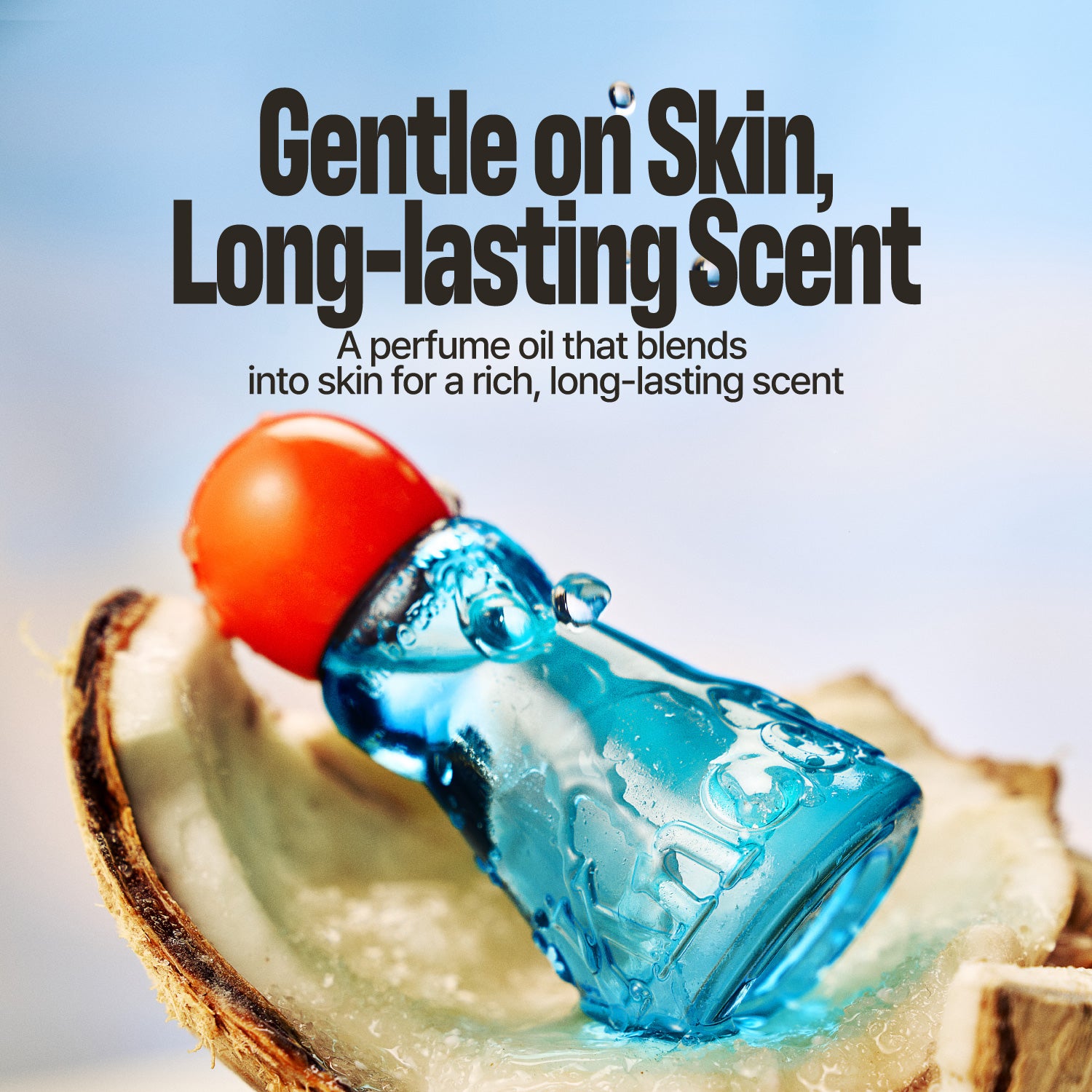 A perfume oil bottle with translucent blue liquid and a bright orange cap, resting on a slice of coconut against a soft light blue background. Large text reads, 'Gentle on Skin, Long-lasting Scent' with smaller descriptive copy below.