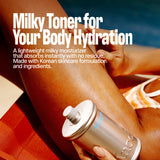 While sitting on a red lounge chair, a person applies MELT IN BODY TONER from its sleek silver bottle to their leg. The description emphasizes the toner’s lightweight, hydrating, and residue-free formula inspired by Korean skincare, noting how it absorbs instantly to provide lasting comfort.
