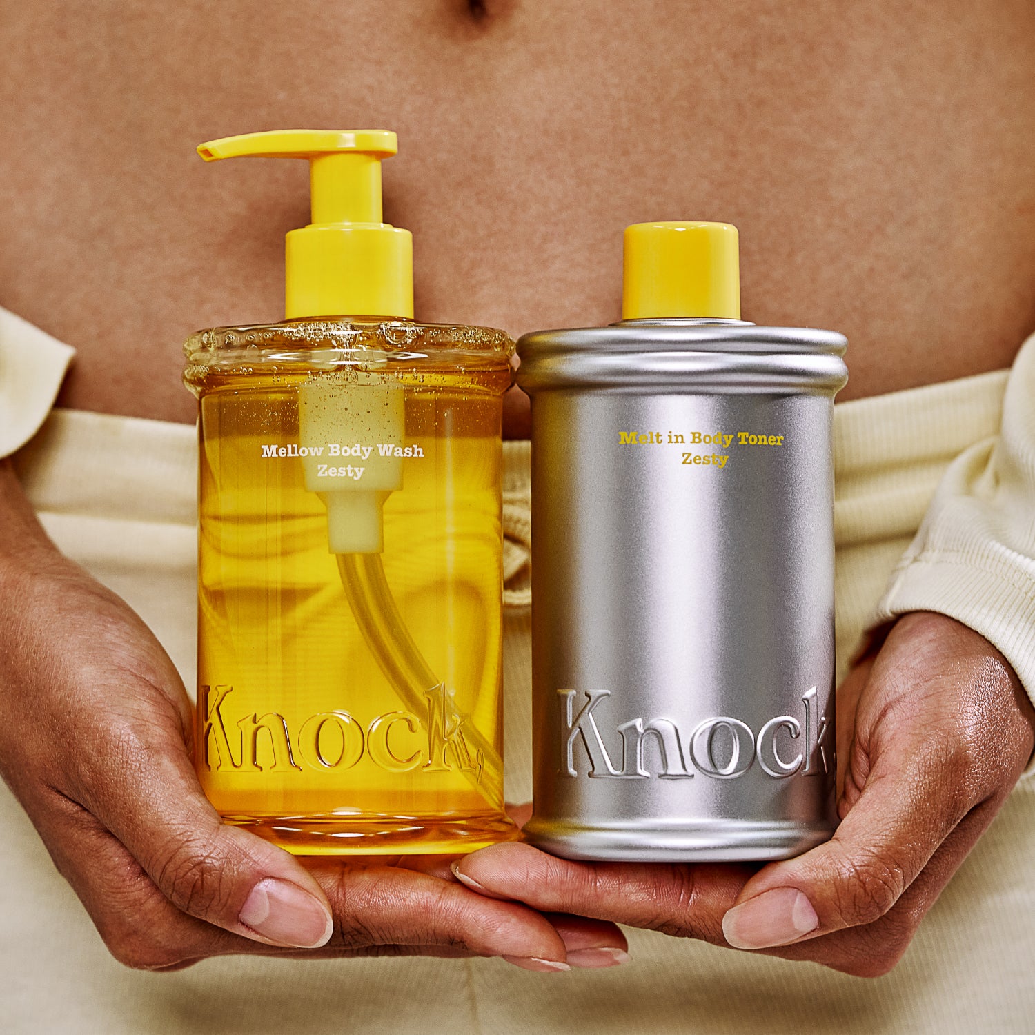 Two bottles of 'Knock' products held by hands against a neutral background